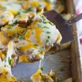 scooping chicken covered in cheese from a sheet pan