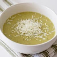 white bowl with zucchini soup with shredded parmesan cheese on top