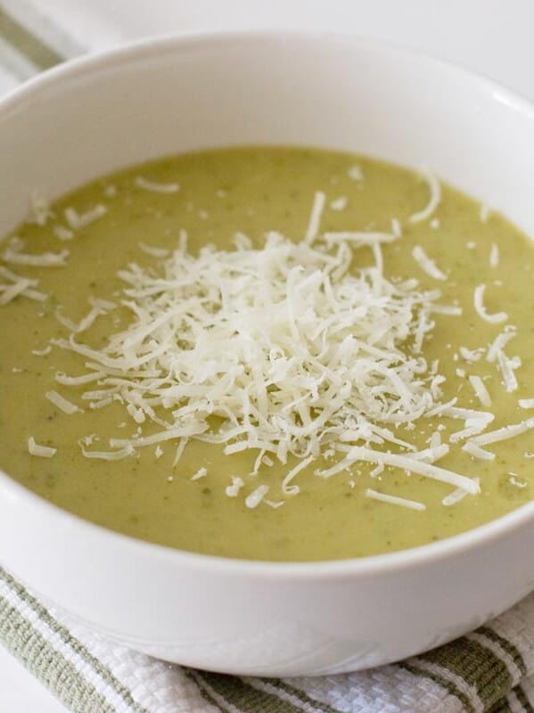 white bowl with zucchini soup with shredded parmesan cheese on top