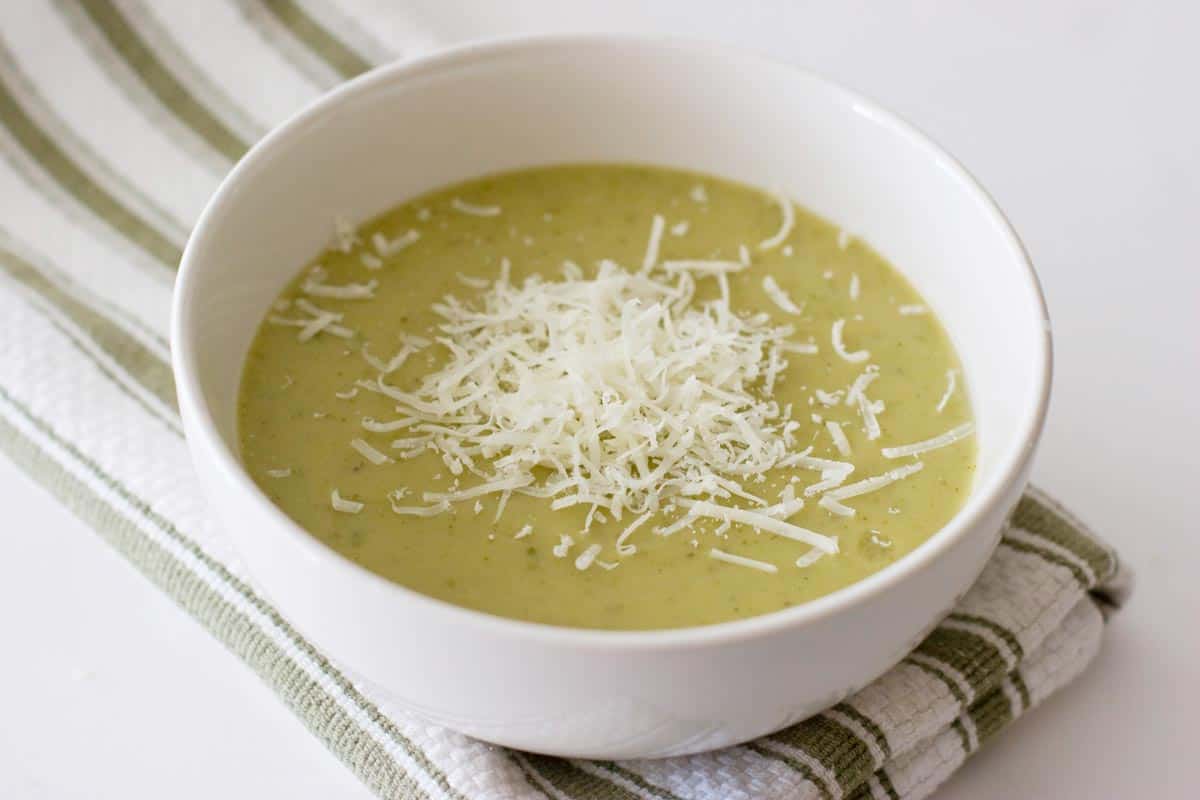 white bowl with zucchini soup with shredded parmesan cheese on top