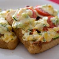 slices of bread topped with tomato, zucchini, bacon and melted cheese