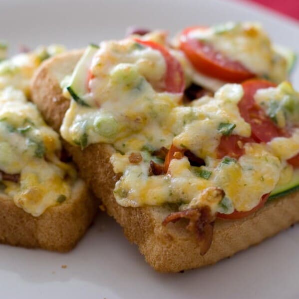 slices of bread topped with tomato, zucchini, bacon and melted cheese