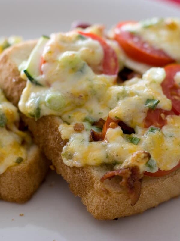 slices of bread topped with tomato, zucchini, bacon and melted cheese