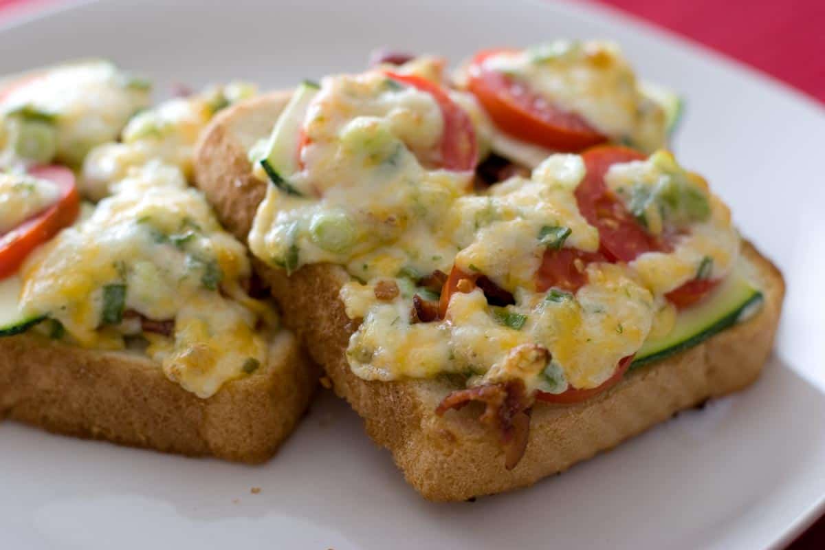 slices of bread topped with tomato, zucchini, bacon and melted cheese