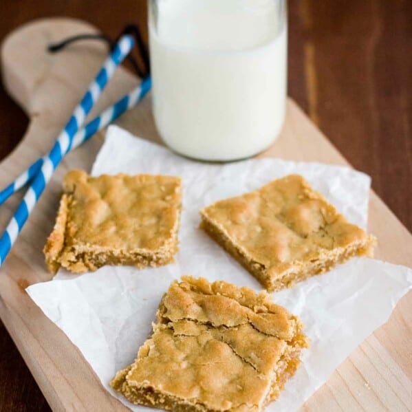 sliced Butterscotch Bars on a cutting board with milk and straws