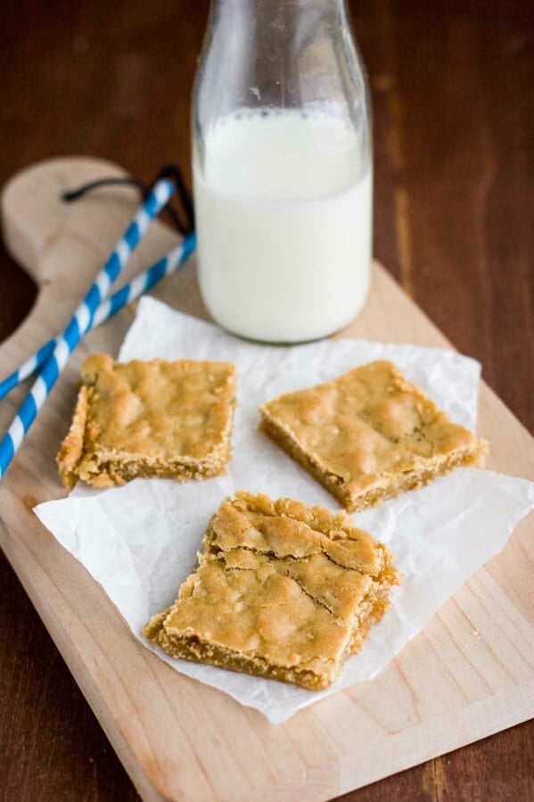 sliced Butterscotch Bars on a cutting board with milk and straws