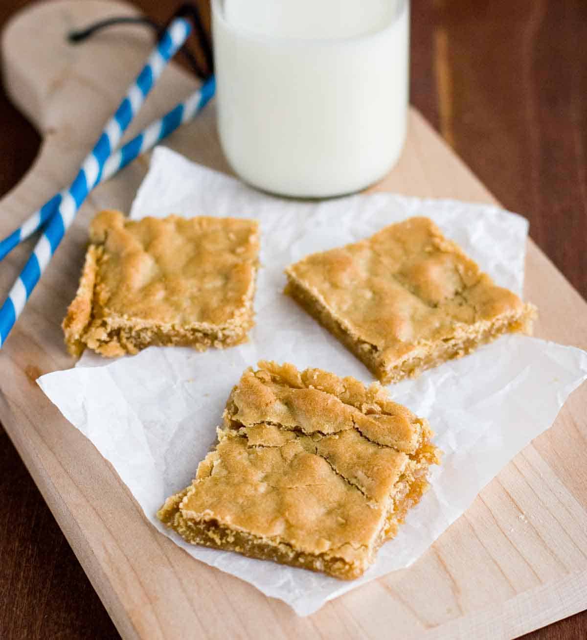 sliced Butterscotch Bars on a cutting board with milk and straws