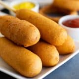 homemade corn dogs on a plate with ketchup and mustard