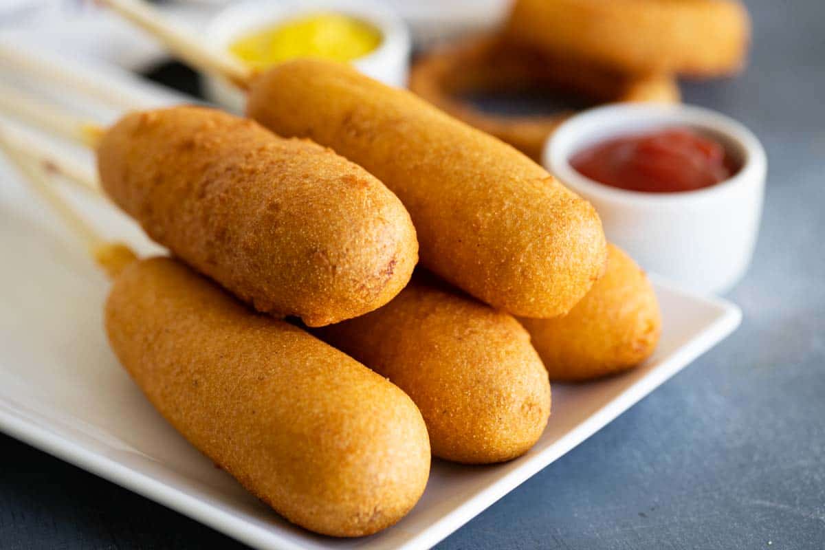 homemade corn dogs on a plate with ketchup and mustard