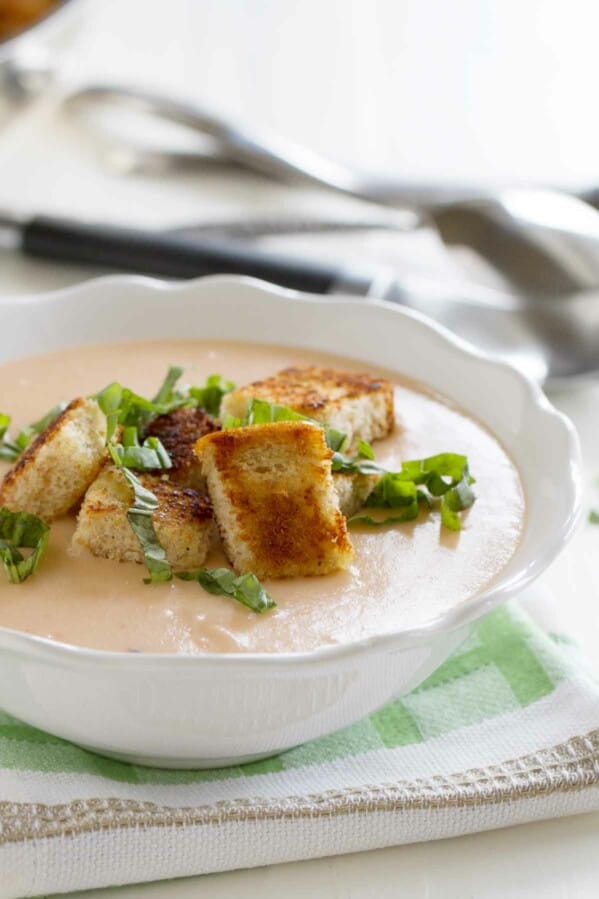 bowl of tomato soup topped with croutons and basil