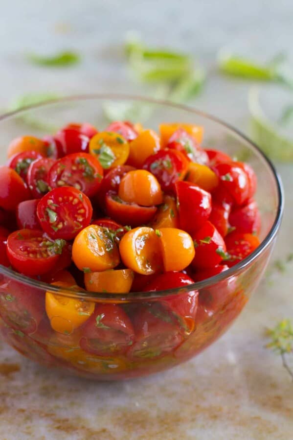 yellow and red grape tomatoes with herbs in a bowl