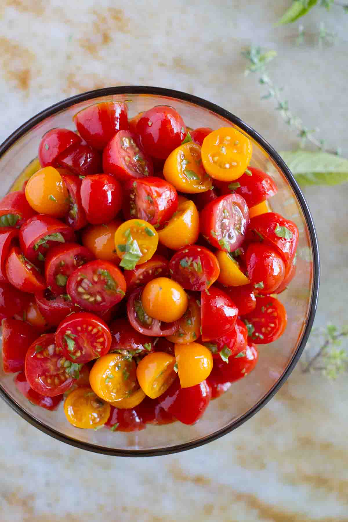 overhead view of sliced grape tomatoes with olive oil and herbs