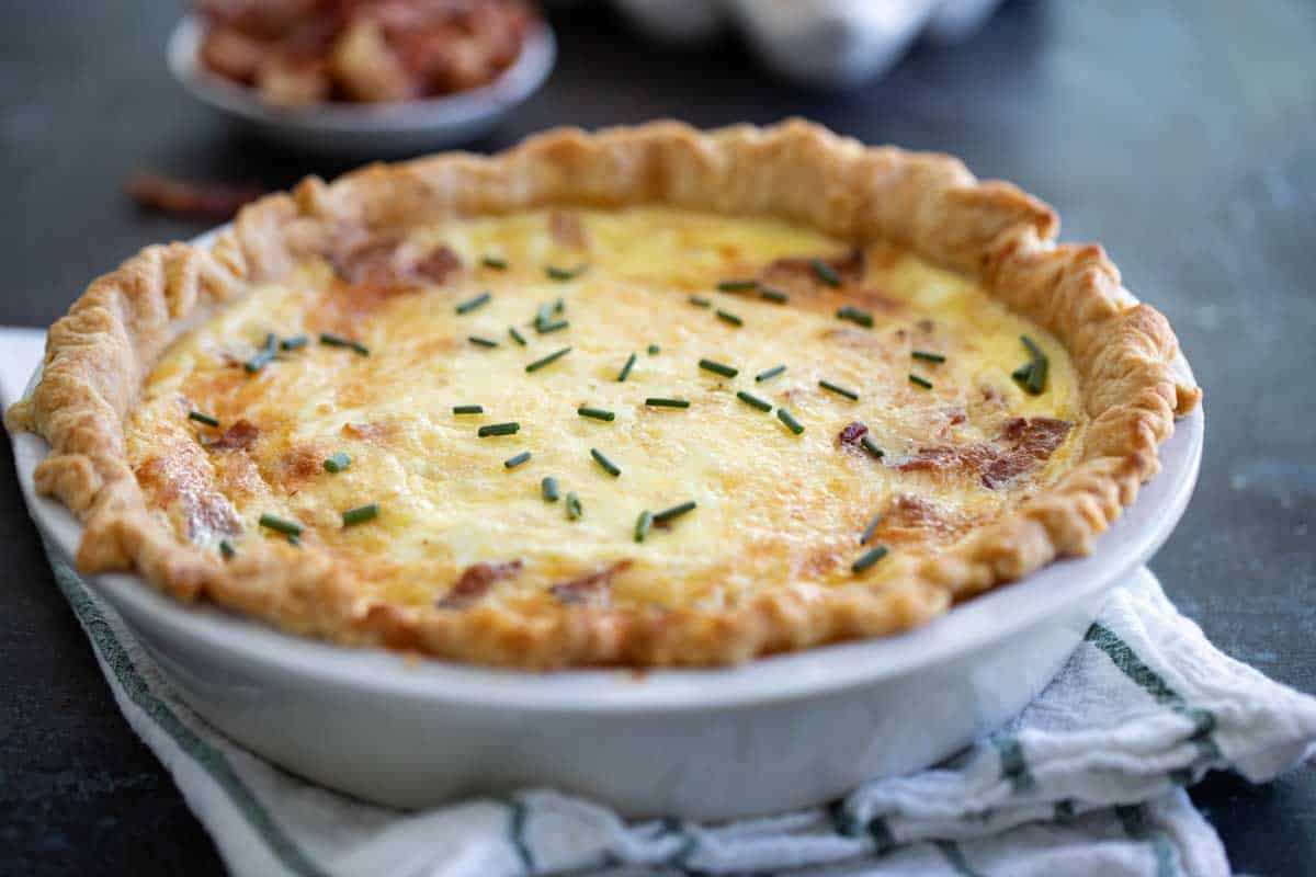 full quiche lorraine in a pie dish on a towel