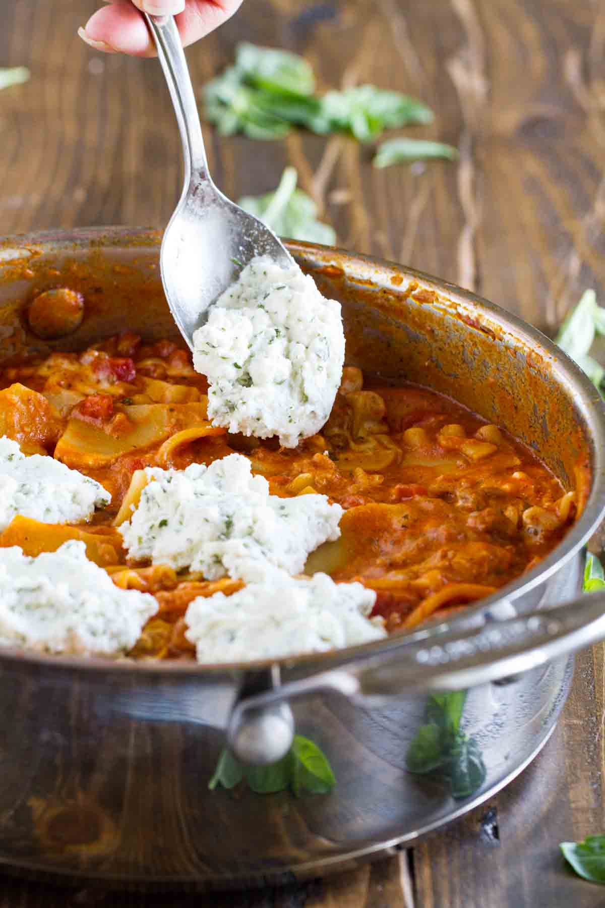 spooning ricotta cheese onto one pan lasagna