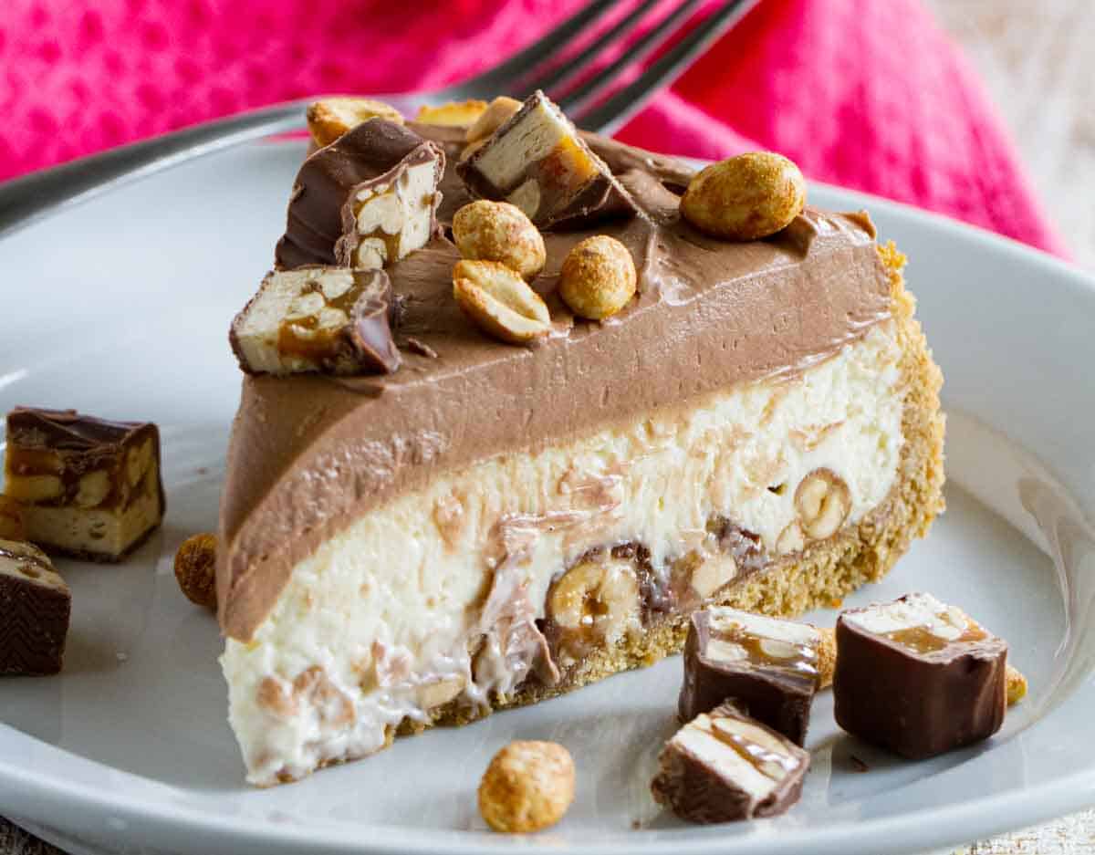 slice of snickers cheesecake with snickers chunks on the side