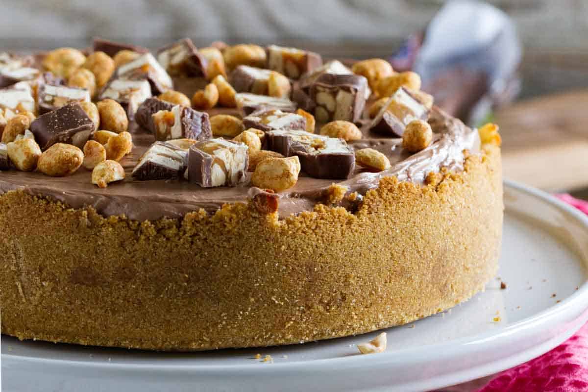 full snickers cheesecake on a serving platter