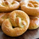 Homemade soft pretzel on a board with a stack of pretzels behind