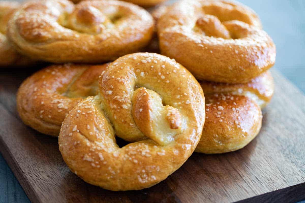 Homemade soft pretzel on a board with a stack of pretzels behind