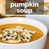 Spicy pumpkin soup topped with cream and pepitas with text overlay