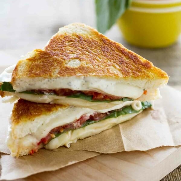 sliced grilled cheese sandwich with tomatoes and basil