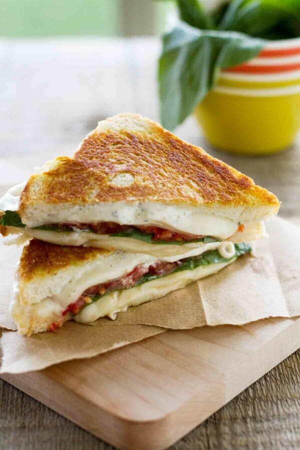 sliced grilled cheese sandwich with tomatoes and basil