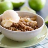 apple crisp in a bowl with a scoop of vanilla ice cream on top