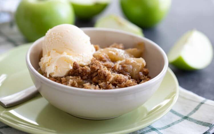 apple crisp in a bowl with a scoop of vanilla ice cream on top