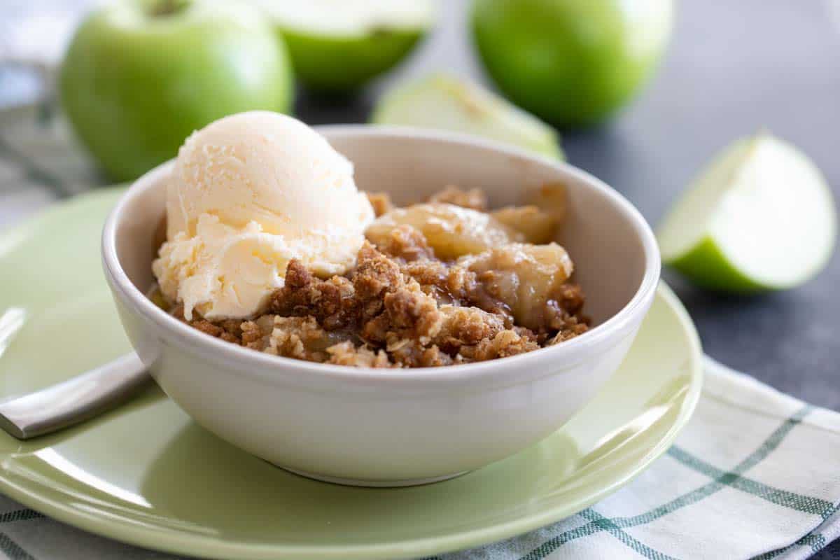 apple crisp in a bowl with a scoop of vanilla ice cream on top