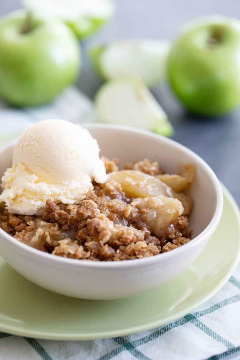 bowl of apple crisp topped with vanilla ice cream