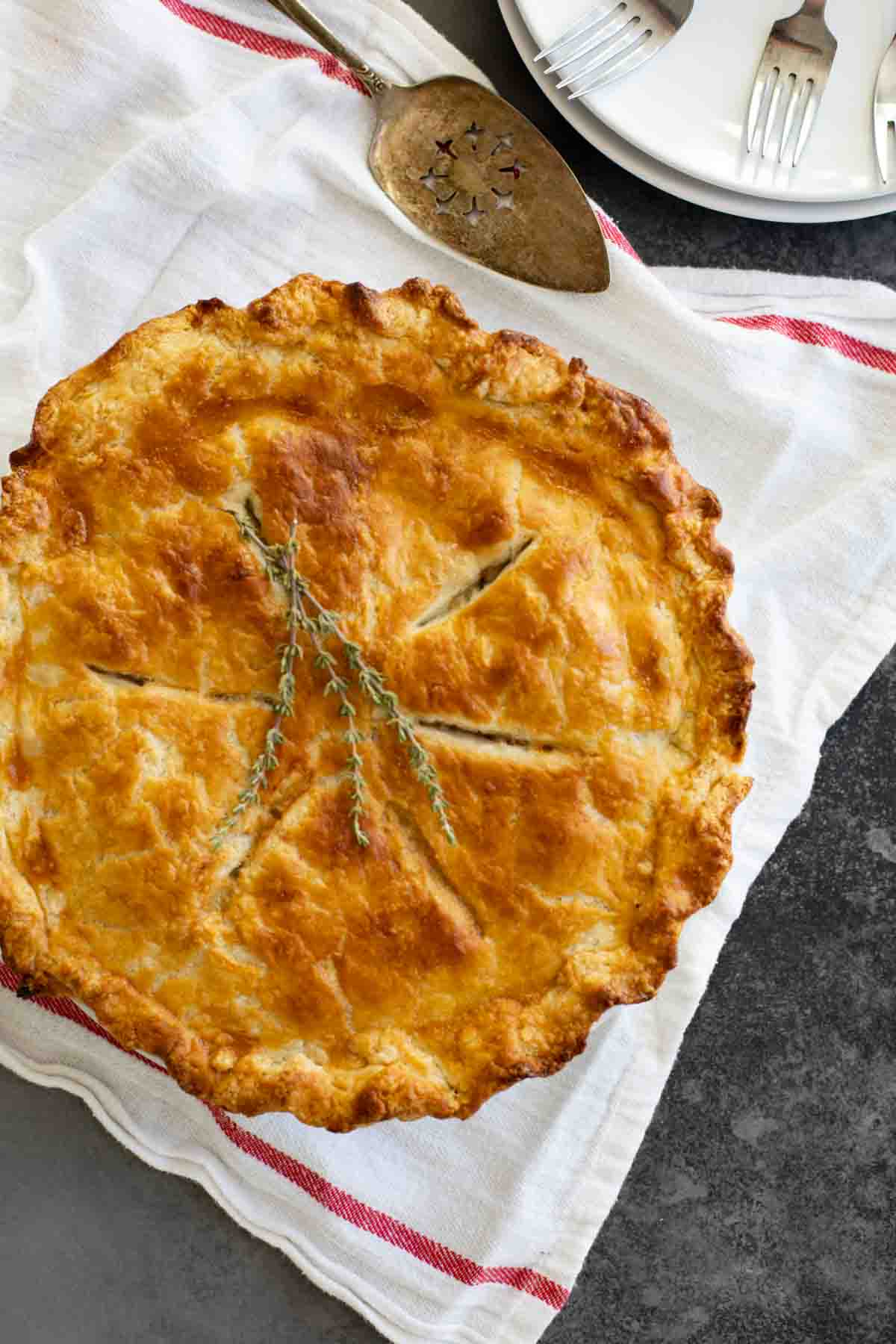 It doesn’t get more comforting than this homemade Chicken Pot Pie recipe! Tender chicken and vegetables are combined with a homemade gravy and baked between two flaky pie crusts. whole chicken pot pie on a cloth