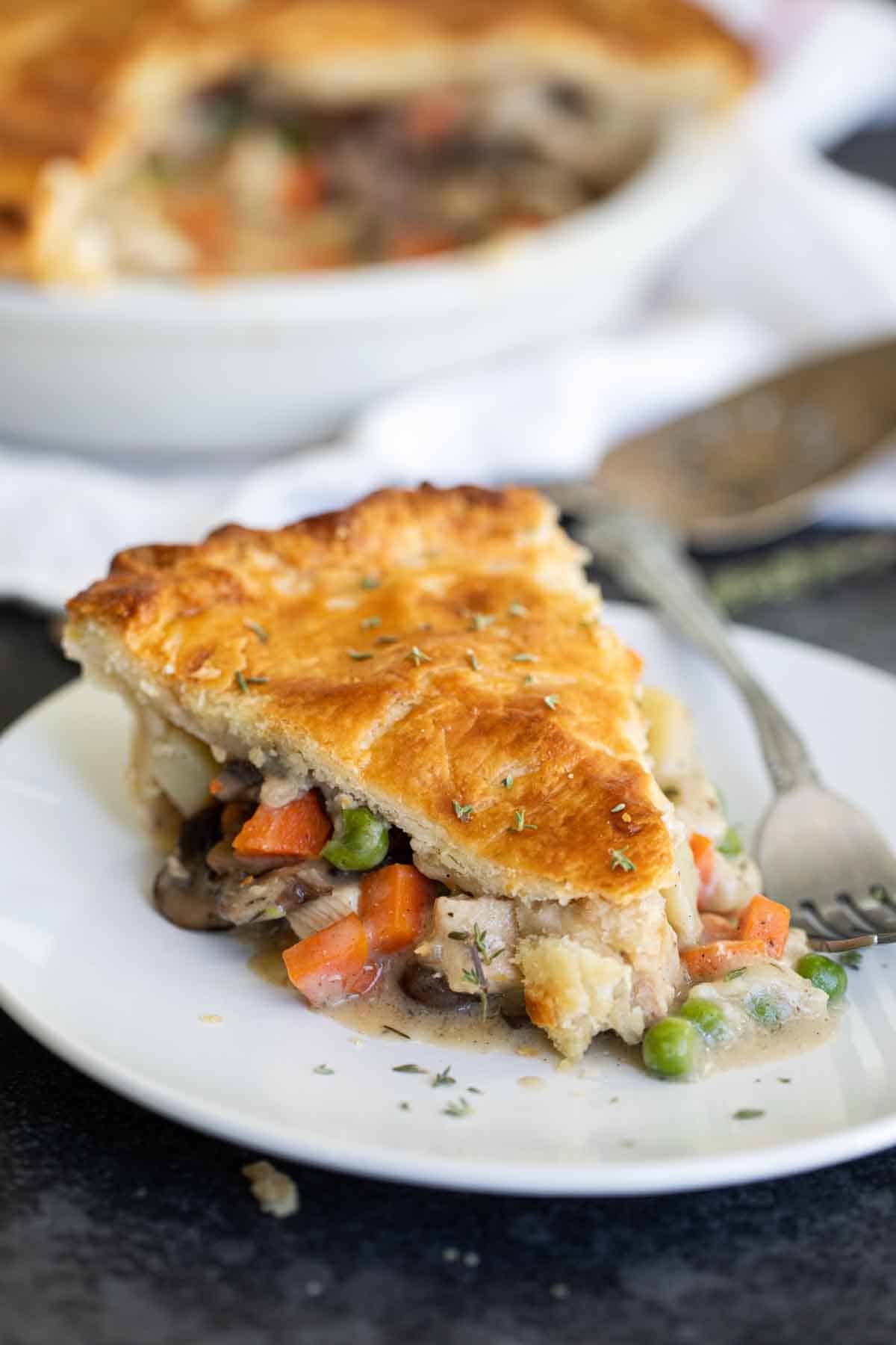 slice of chicken pot pie on a plate with the pan in the background