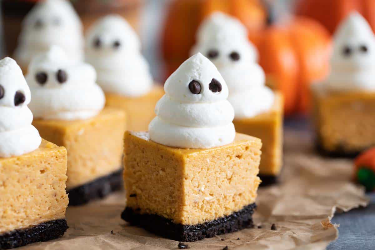 pumpkin cheesecake bars topped with whipped cream ghosts