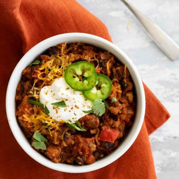 bowl of pumpkin chili on a napkin with a spoon