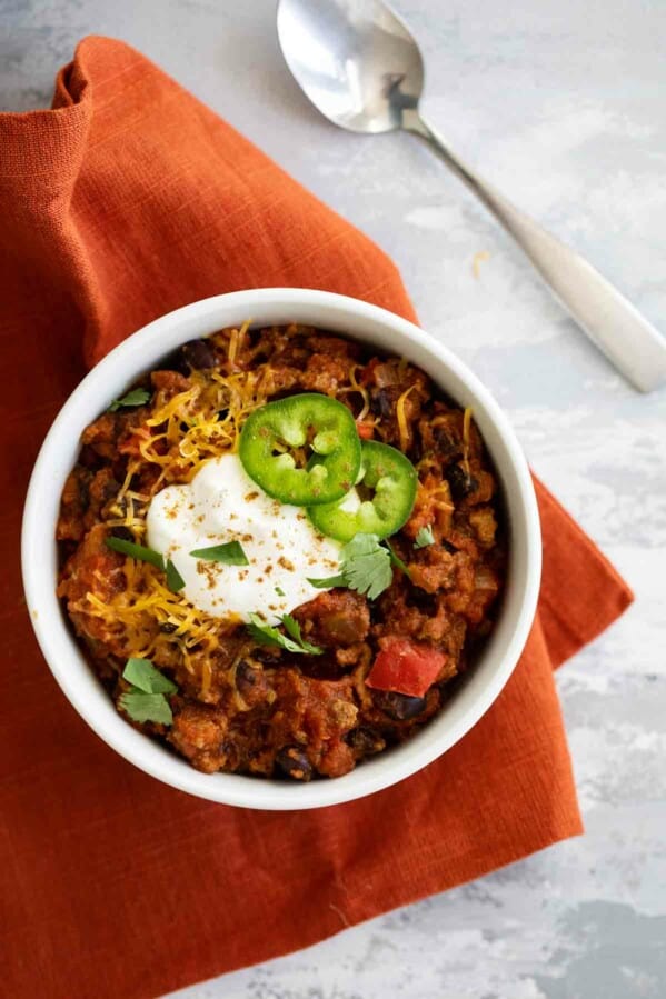 bowl of pumpkin chili on a napkin with a spoon