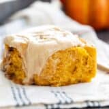 Pumpkin Cinnamon Roll with frosting dripping down the side