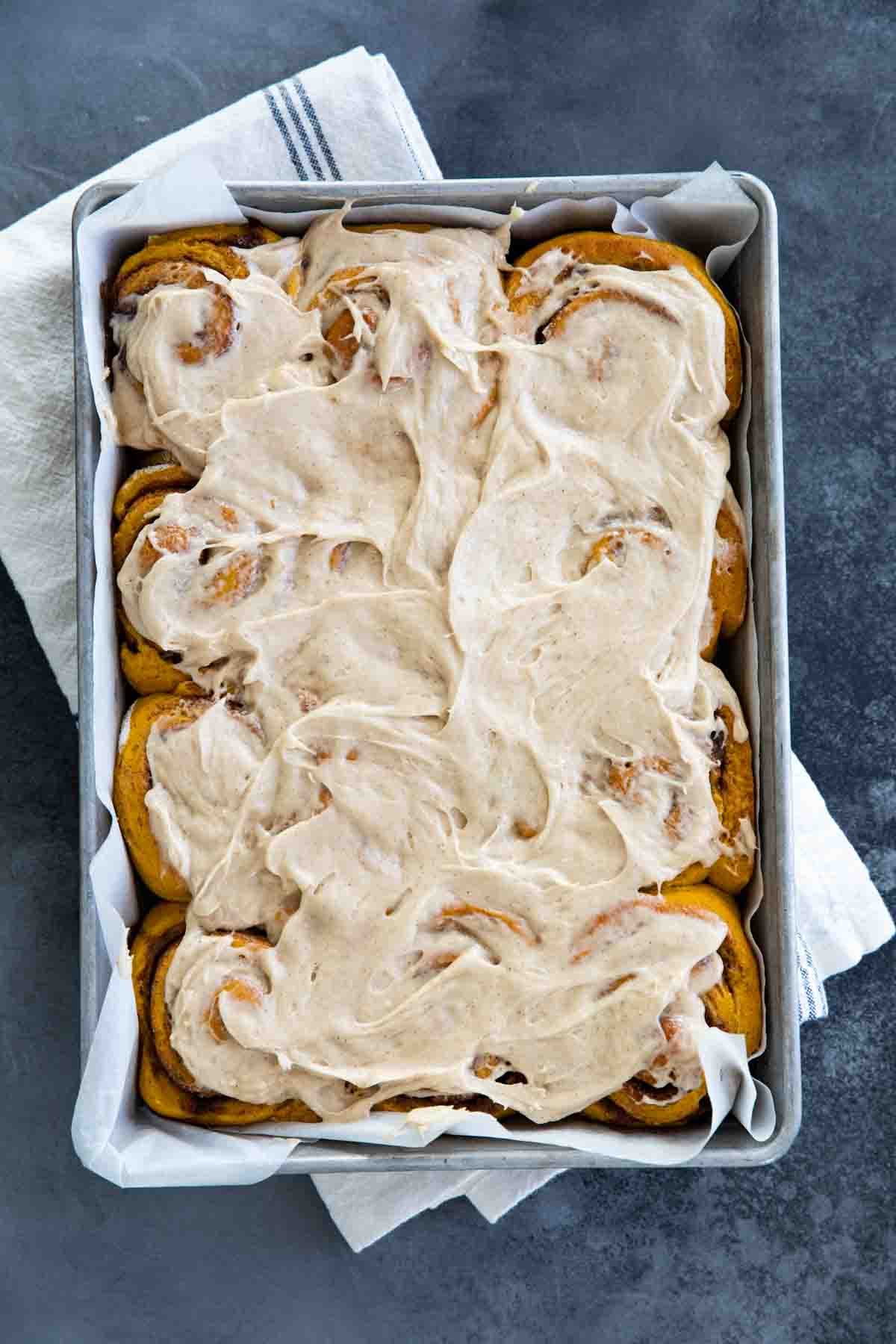 overhead view of pan full of frosted pumpkin cinnamon rolls