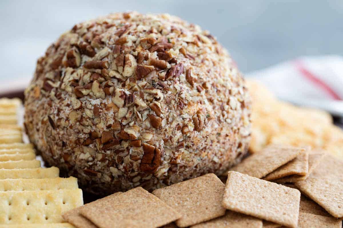 cheese ball coated in pecans surrounded by crackers