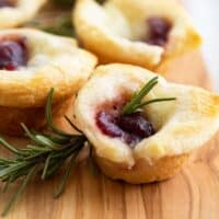 Cranberry Brie Bites with rosemary on a cutting board