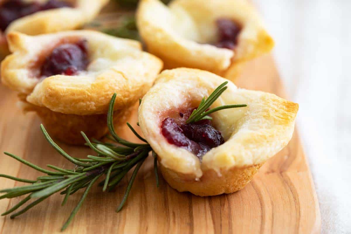 Cranberry Brie Bites with rosemary on a cutting board
