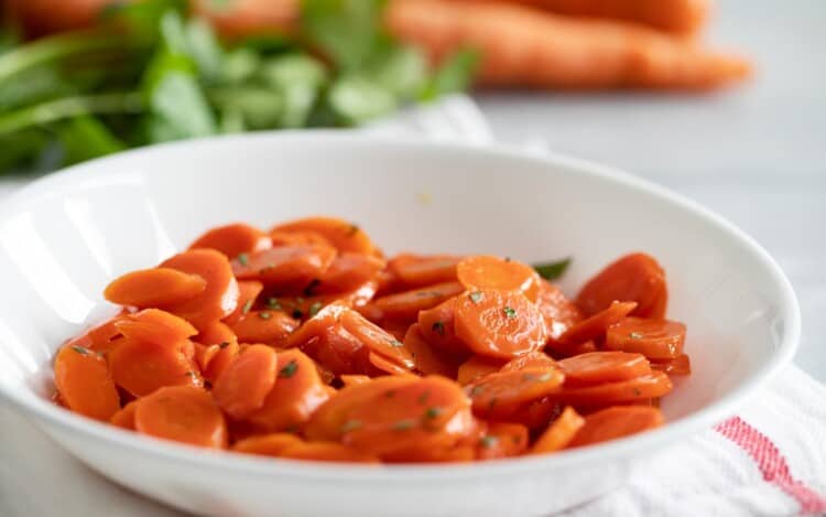 bowl with glazed carrots with parsley sprinkled on top