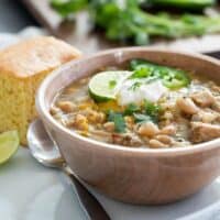 bowl of white turkey chili with cornbread and lime slices