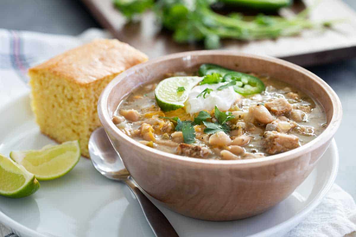 bowl of white turkey chili with cornbread and lime slices