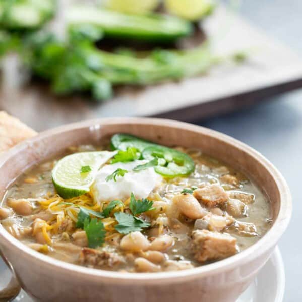 bowl of white turkey chili with beans topped with sour cream and jalapeno