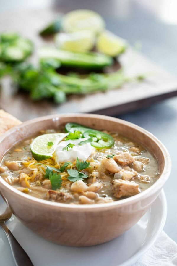 bowl of white turkey chili with beans topped with sour cream and jalapeno