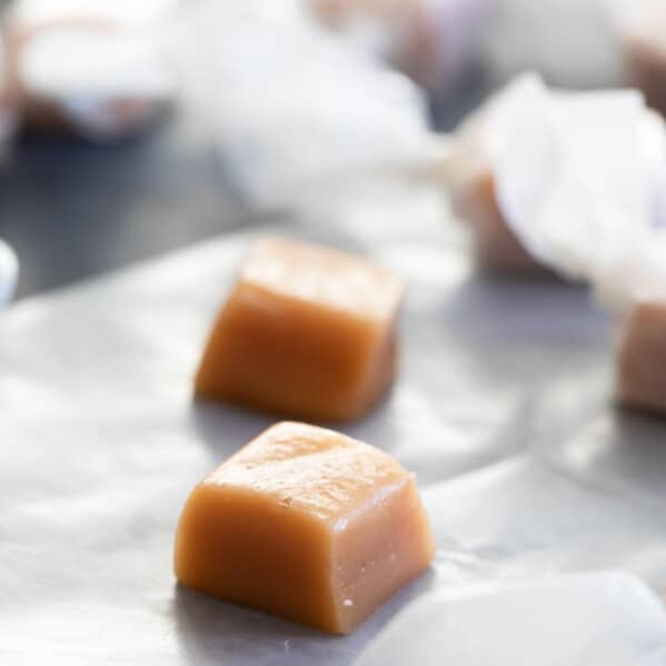 homemade caramel candy on a piece of waxed paper with more candy in the background