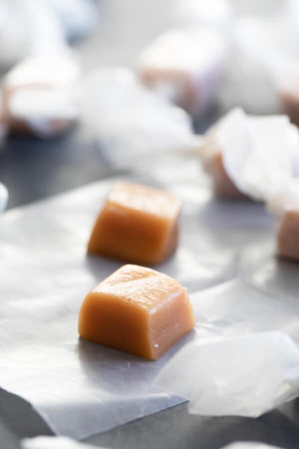 homemade caramel candy on a piece of waxed paper with more candy in the background