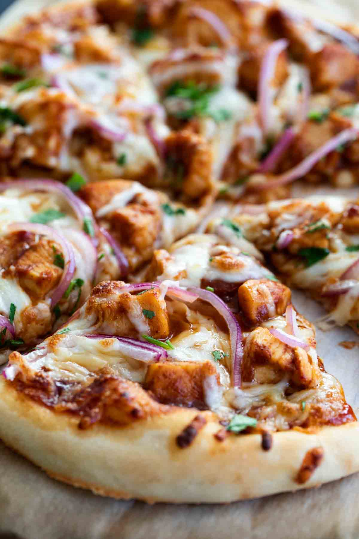bbq chicken pizza topped with bbq sauce, chicken, onions and cilantro