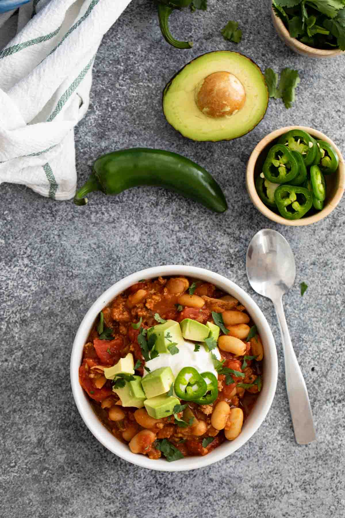 overhead view of a bowl of ground turkey chili with toppings