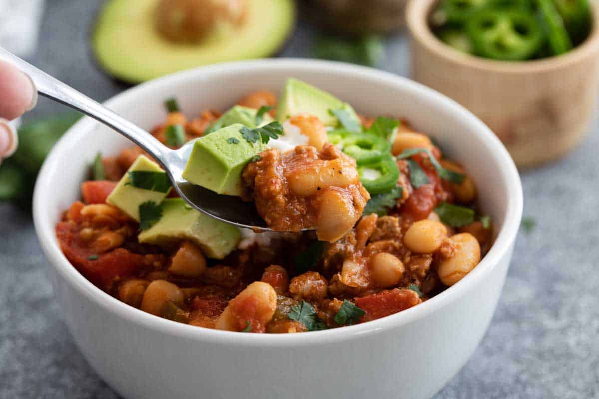 spoonful of ground turkey chili being taken from a bowl of chili