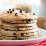 stack of oatmeal pancakes with chocolate chips drizzled with syrup